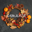 Samhain holiday traditional wreath. autumn wreath with pumpkin, fall leaves, red berries, acorns on dark background. autumn holiday, fall, thanksgiving, halloween concept. Flat lay
