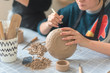 Girl making clay dishes in a workshop, a stage of drawing a pattern