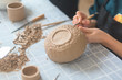 Ceramic girl making clay dishes in a workshop, a stage of drawing a pattern