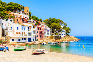 Fishing boats on beach in Sa Tuna village with colorful houses on shore, Costa Brava, Catalonia, Spain