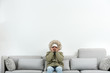 Young man in warm clothes freezing on sofa against white background