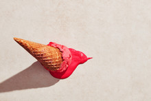 Strawberry Ice Cream With Waffle Cone Dropped On The Floor And Melting On The Ground Under Hot Summer Light