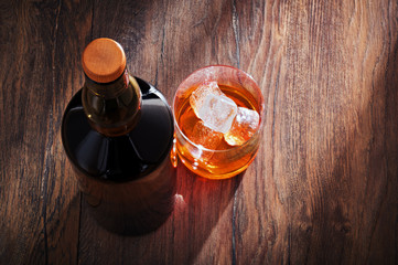 Wall Mural - Whiskey glass with bottle and ice on wooden bar table