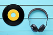 Vinyl record and a headphone on blue wooden table background