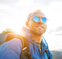 Wall Mural - backpacker man lifestyle portrait enjoying mountain landscape. he wears in blue rain coat poncho and