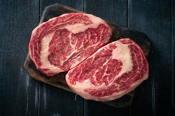 Wall Mural - Perfect raw rib eye beef steak on black wooden background, top view