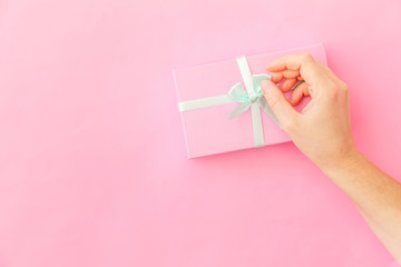 Simply design female woman hand holding pink gift box isolated on pink pastel colorful trendy background. Christmas New Year birthday valentine celebration present romantic concept. Copy space