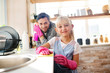 © zinkevych - Cheerful girl wearing pink gloves helping daddy with housecleaning