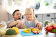 © zinkevych - Blonde daughter smiling while cutting peppers with daddy