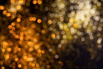 Wall Mural - Abstract blurred glitter bokeh background in gold and orange, on black