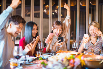 Group of friends having fun at the restaurant and looking at smart phone