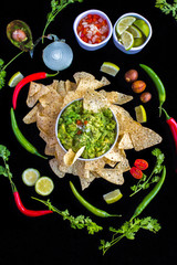 Wall Mural - Guacamole with all the ingredients, authentic mexican recipe on a black background. Includes pico de gallo (tomato, onion and coriander). Top view for instagram