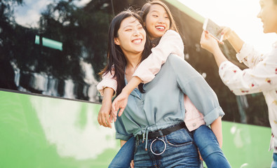 Wall Mural - Happy Asian girls having fun outdoor - Millennial young people sharing time together and using mobile smartphone new trendy apps - Concept of friendship lifestyle with technology