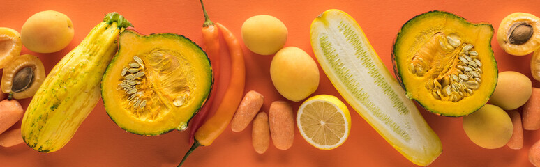 top view of yellow fruits and vegetables on orange background, panoramic shot