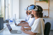 © Mangostar - Diverse professionals testing new VR software. Man and women wearing VR headset, sitting at workplaces with laptops. Virtual reality technology concept