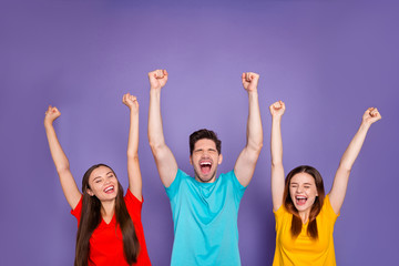 Portrait of nice attractive lovely content cheerful cheery glad guys wearing colorful t-shirts celebrating good news accomplishment rising hands up isolated over violet lilac background