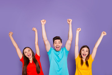 Poster - Portrait of nice attractive lovely content cheerful cheery glad guys wearing colorful t-shirts celebrating cool accomplishment having fun rising hands up isolated over violet lilac background