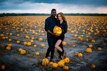 Couple Standing In Pumpkin Field And Holding Scary Face Pumpkin, Concept Halloween