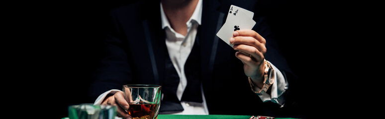 panoramic shot of man holding playing cards isolated on black