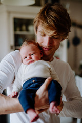 Wall Mural - A front view of young father holding a newborn baby at home.