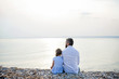 © Halfpoint - Rear view of father and small daughter on a holiday sitting by the lake.