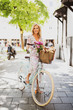 Attraktive Frau in sommerlichem Kleid ist mit dem Fahrrad in der Stadt unterwegs 