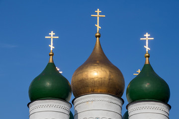 Three domes of the church in the city of Kolomna, one gilded and two painted green, with crosses.