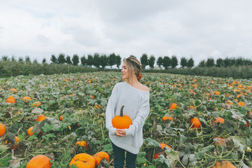 a beautiful woman in a pumpkin patch in fall.