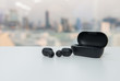 True wireless earbuds with battery case on the white table with blur city scape background