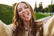 © Drobot Dean - Beautiful young ginger woman take selfie by camera showing tongue.