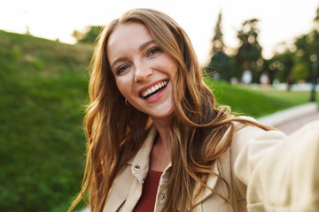 ginger woman walking in park outdoors take selfie by camera.