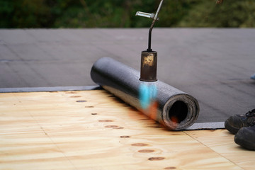 Bitumen roofing.,  with a gas burner and a roll of tar paper. Flat roof installation.