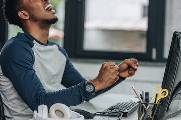 angry african american programmer gesturing while sitting at workplace in office