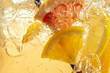 Close up of lemon slices in stirring the lemonade and ice cubes on background. Texture of cooling sweet summer's drink with macro bubbles on the glass wall. Fizzing or floating up to top of surface.