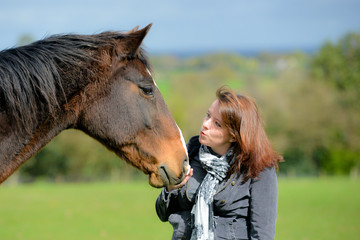 Wall Mural - Pretty young woman and her bay horse sharing a loving moment in the field on a summers day.