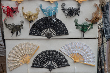 Group of small vintage Venetian carnival masks in fabric and fans. On the sales counter, Halloween party Venice carnival mask. For masquerade parties, Cosplay, Valentine's Day.