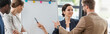 © LIGHTFIELD STUDIOS - panoramic shot of four smiling multiethnic colleagues in formal wear standing near flipchart in office