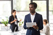 © LIGHTFIELD STUDIOS - african american businessman in formal wear holding digital tablet in office