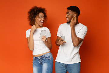 Wall Mural - Happy man and woman listening to same track on cellphones