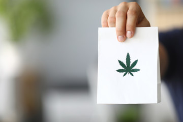 Courier hand passing package with marijuana to client close-up