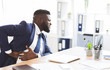 © Prostock-studio - African young businessman holding his side, suffering from liver pain