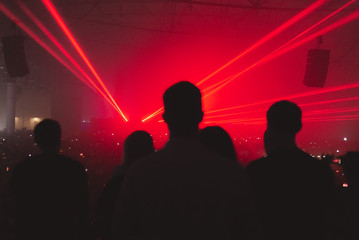 Silhouettes of fans at a music festival. Bright spotlights at the concert.