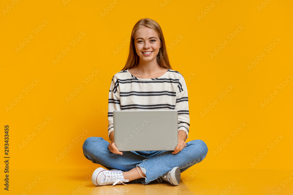 Beautiful young girl sitting with laptop on laps - obrazy, fototapety, plakaty 