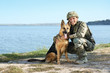 © New Africa - Man in military uniform with German shepherd dog near river, space for text