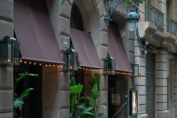 Wall Mural - Blank brown black awning over cafe windows mockup. Empty awning mounted on the ancient wall in european town.