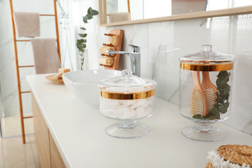 Jars with cotton pads and hairbrushes on bathroom countertop