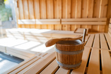Indoor Of A Finnish Sauna, With A Water Bucket And Sunlight Shining Through A Big Window, Spa And Wellness Concept In A Hotel