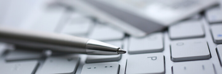 silver pen with credit card lie white keyboard pc buttons closeup. financial transfer security when 