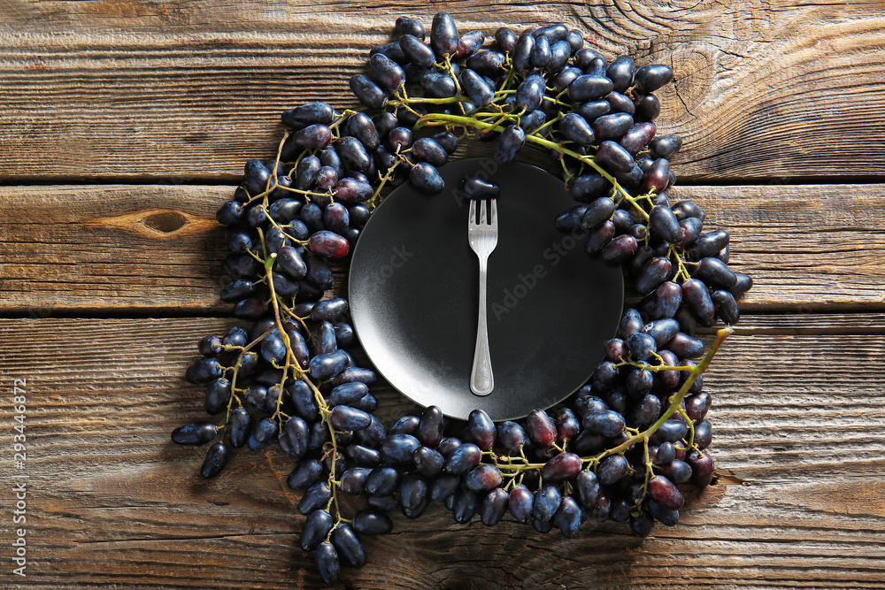 Plate with tasty sweet grapes on wooden table
