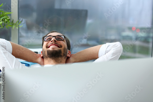 Fotografía Handsome smiling bearded adult clerk person arms crossed up over head sit behind laptop pc display at office workplace desk portrait